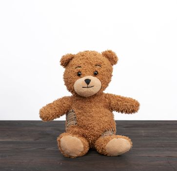 brown teddy bear sits on a brown wooden table, close up