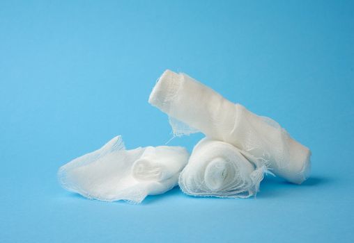 stack of white medical gauze cotton bandages on a blue background, close up