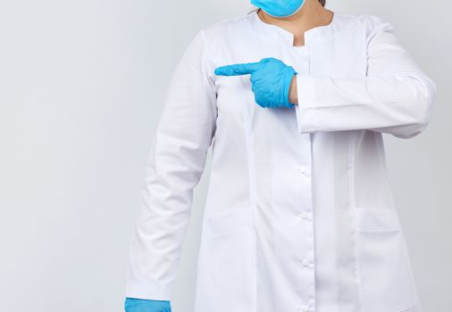 medic woman in white coat with buttons on her hands, wearing blue sterile gloves, showing hand gesture indicating the subject, white background