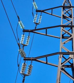 fragment of a metal tower with power lines against a blue sky