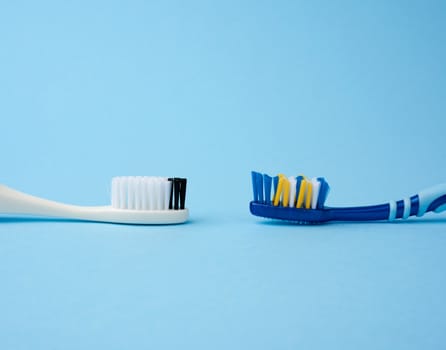 two plastic toothbrushes on a blue background, copy space