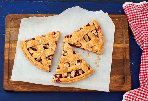 round traditional baked cherry pie, blue wooden table, top view