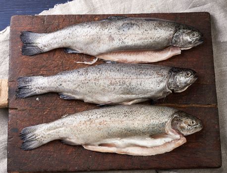 fresh peeled trout fish on a brown cutting board, top view