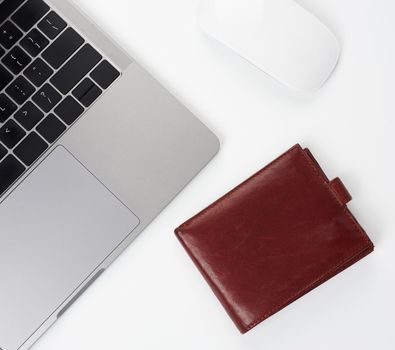 open gray laptop stands on a white table, next to a wireless mouse, freelancer workplace, businessman, top view