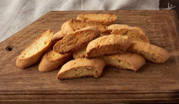 pieces of baked italian christmas biscotti cookies on a brown wooden board, close up