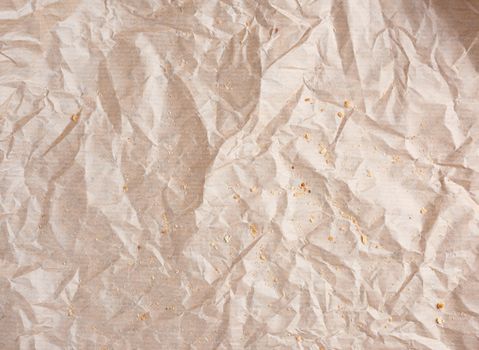 crumpled brown parchment paper with bread crumbs, full frame