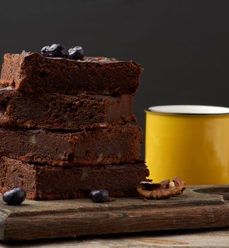 square baked slices of brownie chocolate cake with walnuts on a wooden surface. Cooked homemade food. Chocolate pastry. Sweet meal, homemade dessert