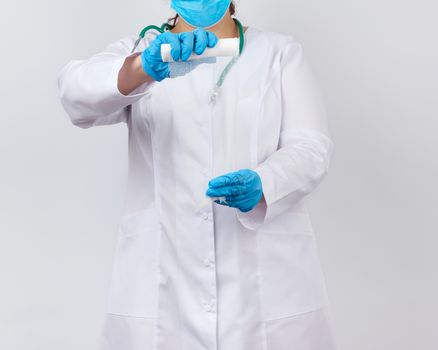 medic woman in white coat and mask holds a twisted gauze bandage for dressing wounds, white background