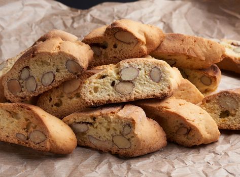 pieces of baked italian christmas biscotti cookies on a brown crumpled paper, close up