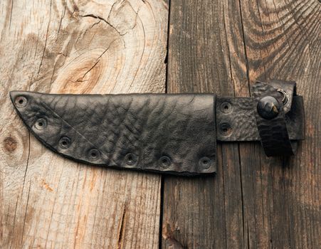leather case for a knife lies on a gray wooden background, close up