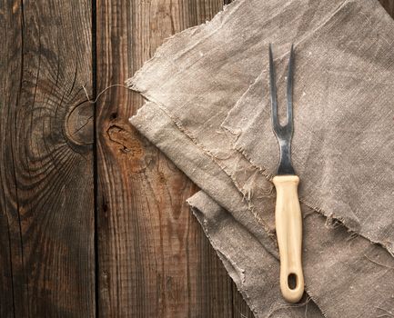 vintage kitchen fork for meat lies on a gray linen napkin, top view, place for an inscription, flat lay