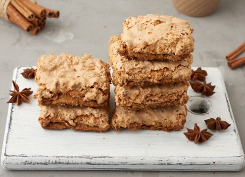 stack of baked Krakow meringue cookies on a wooden board and ceramic cup with black coffee, delicious dessert of whipped egg whites and almond flour