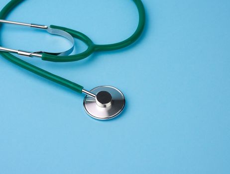green metal medical stethoscope on a blue background, close up