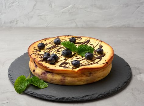 baked round cottage cheese casserole on a black plate, tasty and healthy dessert