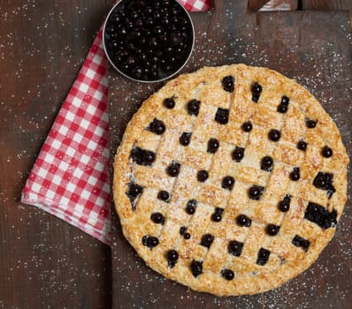 baked round black currant pie on wooden cutting board, top view