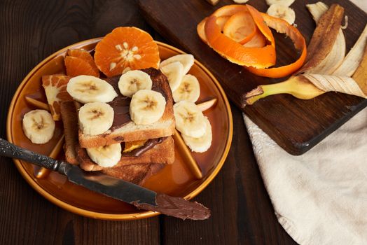 toasted sandwiches with chocolate paste and banana slices on a plate, morning breakfast, close up