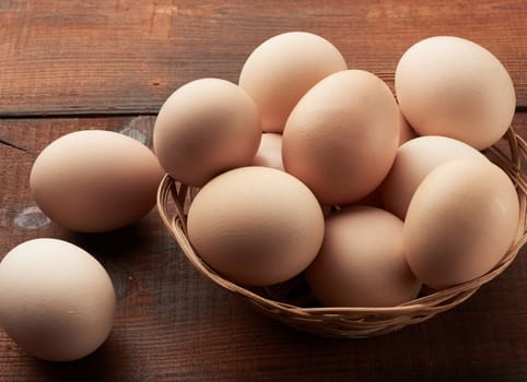 raw brown chicken eggs in a wooden plate on the table, top view