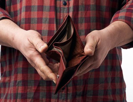 man in a red plaid shirt holds an empty leather brown wallet, concept of poverty and economic crisis