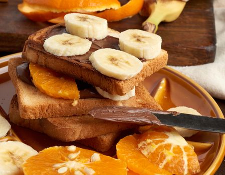 sandwiches with chocolate paste and banana slices on a plate, morning breakfast