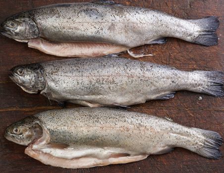 fresh peeled trout fish on a brown cutting board, top view