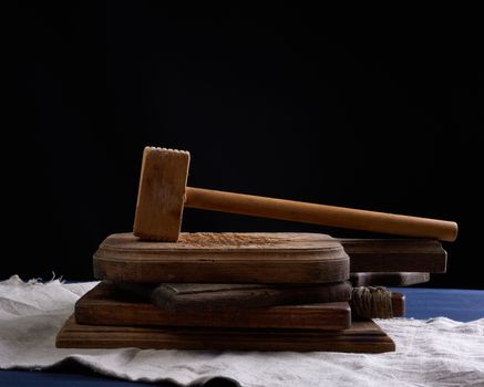 wooden vintage kitchen hammer for chopping meat on a cutting board, black background