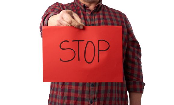 adult man in a red checkered crumpled shirt holds a red sheet of paper with the inscription stop, concept stop panic