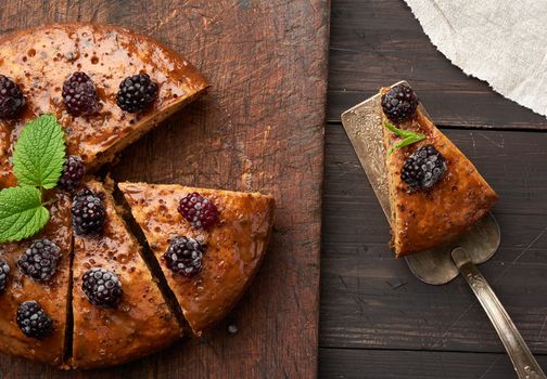 baked round biscuit cake with nuts and berries topped, wooden brown table, top view