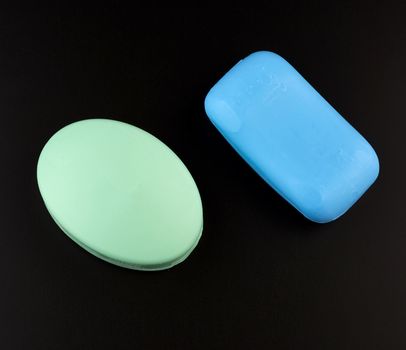 blue and green soaps on a black background, top view