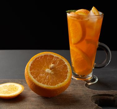  large glass with a handle filled with lemonade with slices of orange and lemon, black background