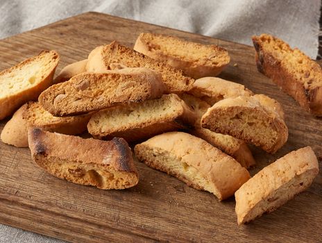 pieces of baked italian christmas biscotti cookies on a brown wooden board, close up