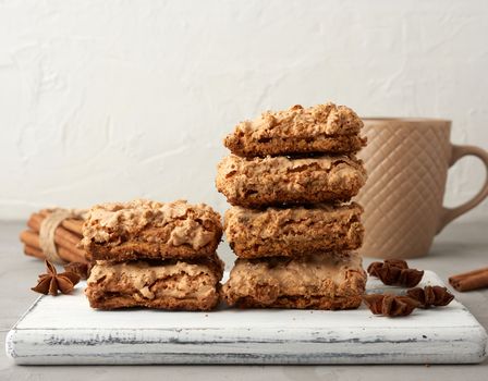 stack of baked Krakow meringue cookies on a wooden board and a white ceramic cup with black coffee, delicious dessert of whipped egg whites and almond flour