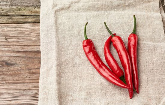 raw red chili peppers on a gray linen towel, gray wooden table, close up