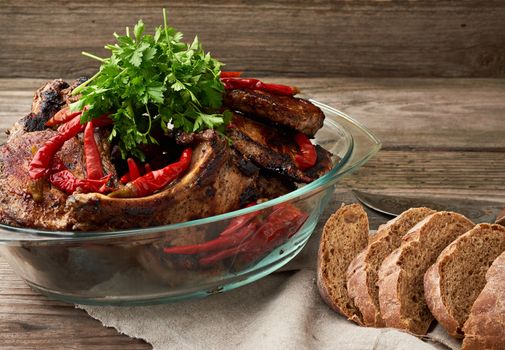 grilled pork steaks on the bone lie in a transparent glass plate on a wooden table, barbecue