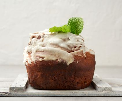 baked Easter cake with white lemon glaze on a white wooden board, traditional orthodox pastries