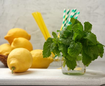 yellow ripe lemon and a bunch of fresh green mint on a wooden board, ingredients for lemonade