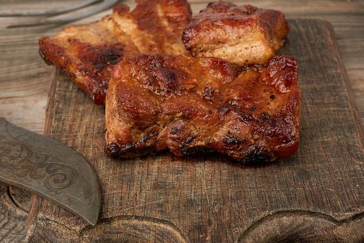 fried pork ribs on a brown wooden board, close up