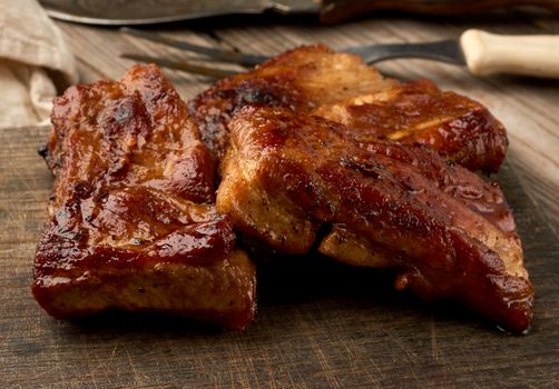 fried juicy pork meat on the bone on a wooden board, grilled meat, close up