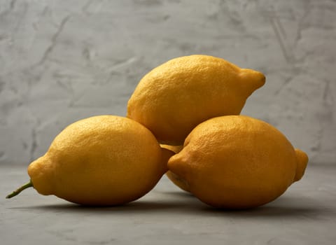 ripe yellow lemons on a gray table, ingredient for lemonade, close up