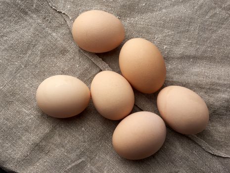 whole broken raw brown homemade chicken eggs on a gray linen napkin, top view