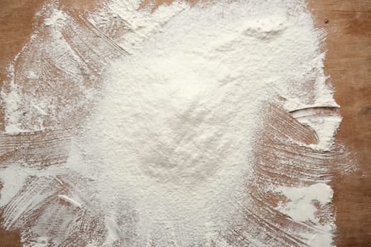 slide of white wheat flour sprinkled on a brown wooden table, top view