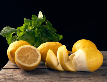 yellow ripe lemon and a bunch of fresh green mint on a wooden board, ingredients for lemonade