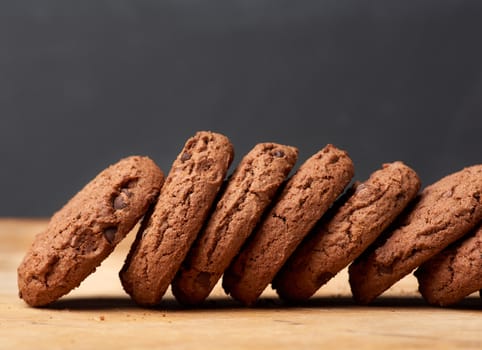 stack of baked round chocolate chip cookies on a brown wooden table, close up