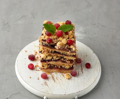 stack of square slices of baked crumble pie with blue plum on a white wooden board, delicious dessert, top view
