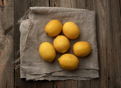 yellow round lemons on a gray textile napkin, top view
