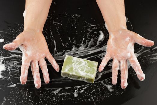 process of washing hands with blue soap, parts of the body in white foam on a black background, top view, hygiene concept