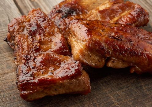 fried pork ribs on a brown wooden board, close up