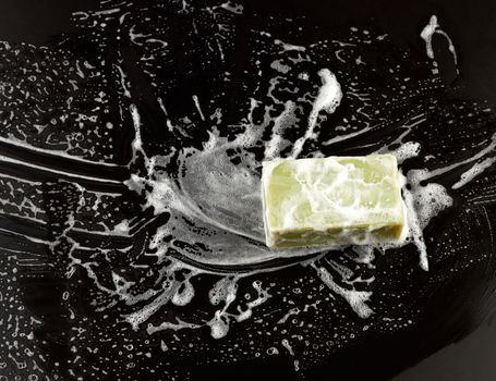 white soap foam and green soap on a black background, top view, concept of cleanliness, antibacterial