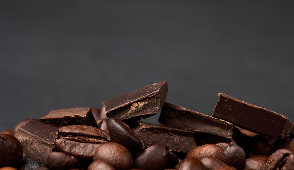 pieces of dark chocolate and roasted brown grains of Robusta coffee, copy space