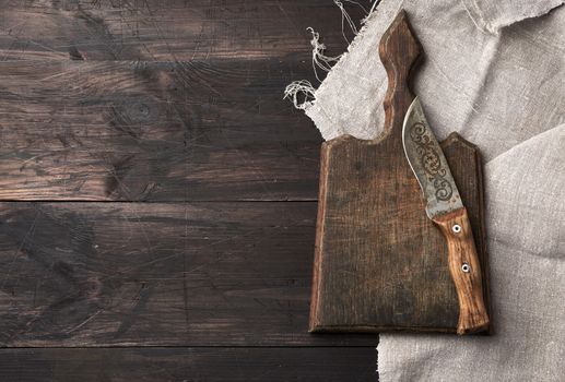empty old wooden cutting board and vintage knife on the table, top view