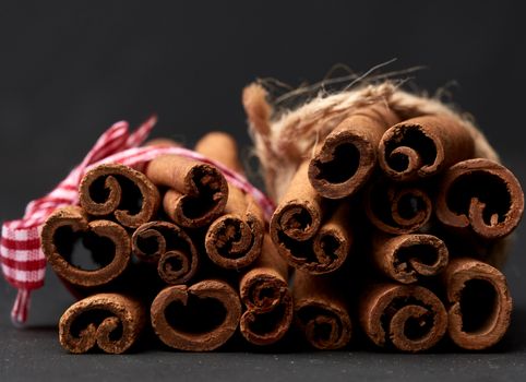 tied bunch of brown cinnamon sticks on a dark background, close up